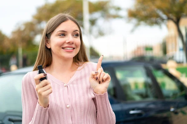 Young pretty blonde woman holding car keys at outdoors intending to realizes the solution while lifting a finger up