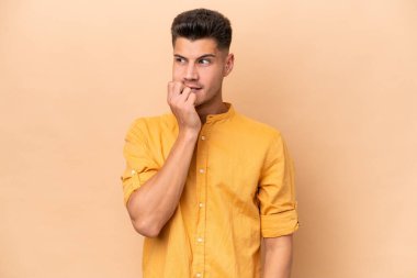 Young caucasian man isolated on beige background nervous and scared