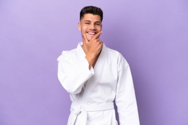Morarmış arka planda karate yapan genç beyaz adam mutlu ve gülümsüyor.
