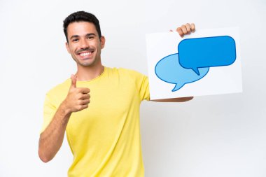 İzole edilmiş beyaz arka plan üzerinde genç yakışıklı bir adam elinde baş parmağıyla konuşma baloncuğu ikonu taşıyan bir pankart tutuyor.