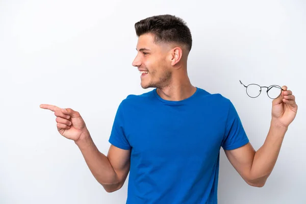 stock image Young caucasian man holding glasses isolated on white background pointing to the side to present a product