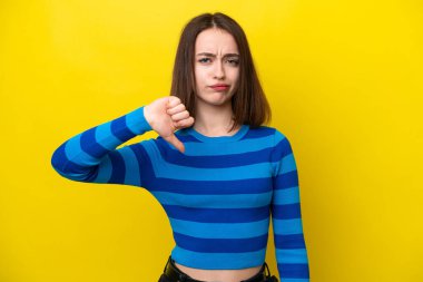 Young Ukrainian woman isolated on yellow background showing thumb down with negative expression