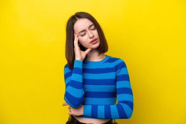 Young Ukrainian woman isolated on yellow background with headache