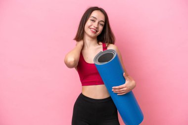Genç sporcu Ukraynalı kadın yoga derslerine giderken elinde pembe arka planda izole edilmiş bir minder tutarken gülüyor.