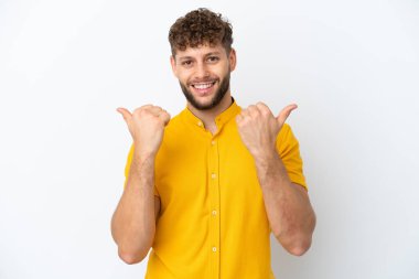 Beyaz arka planda soyutlanmış yakışıklı beyaz bir adam. Baş parmakları havada ve gülümsüyor.