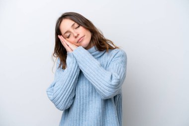 Beyaz arka planda izole edilmiş genç beyaz kadın uyku jesti yapıyor.