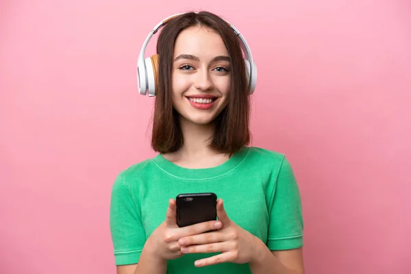 우크라이나 소녀가 휴대폰으로 음악을 바라보며 분홍색 배경에 고립되어 있었다 — 스톡 사진