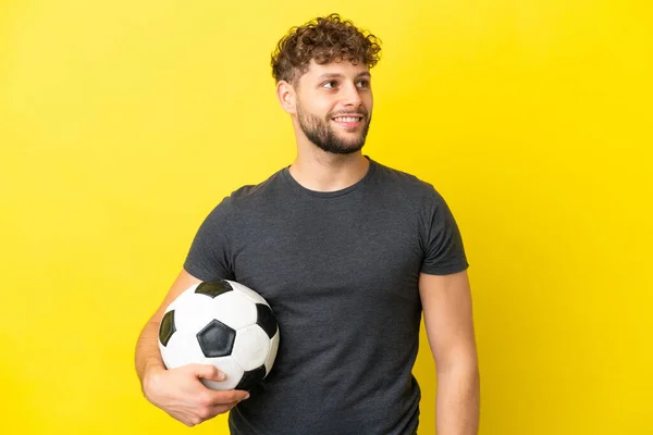 Όμορφος Νεαρός Ποδοσφαιριστής Απομονωμένος Κίτρινο Φόντο Σκέφτεται Μια Ιδέα Ενώ — Φωτογραφία Αρχείου