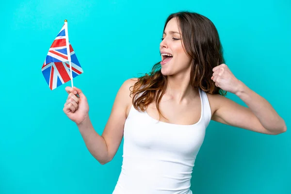 勝利を祝う青の背景に隔離された英語の旗を持つ若い白人女性 — ストック写真