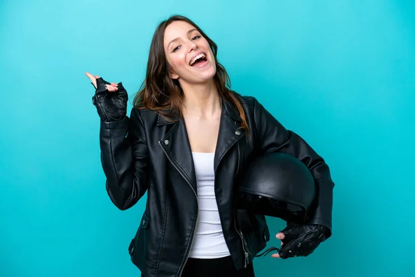 若いですCaucasian女性とともにオートバイヘルメット隔離上の青背景笑顔とショー勝利サイン — ストック写真