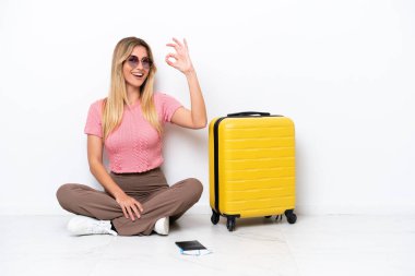 Uruguaylı gezgin kadın, beyaz arka planda izole bir şekilde yerde oturuyor. Parmaklarıyla işaret veriyor.