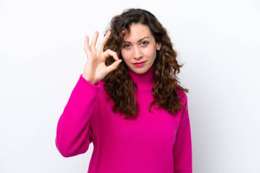 Beyaz arka planda izole edilmiş genç beyaz kadın parmaklarıyla tamam işareti gösteriyor.