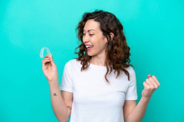 Young caucasian woman holding a envisaging isolated on blue background celebrating a victory