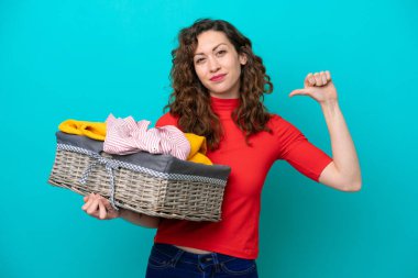 Mavi arka planda soyutlanmış, gururlu ve kendini beğenmiş bir elbise sepeti tutan beyaz bir kadın.