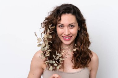 Beyaz arka planda, elinde okaliptüs dalı tutan beyaz tenli bir kadın. Portreyi kapat