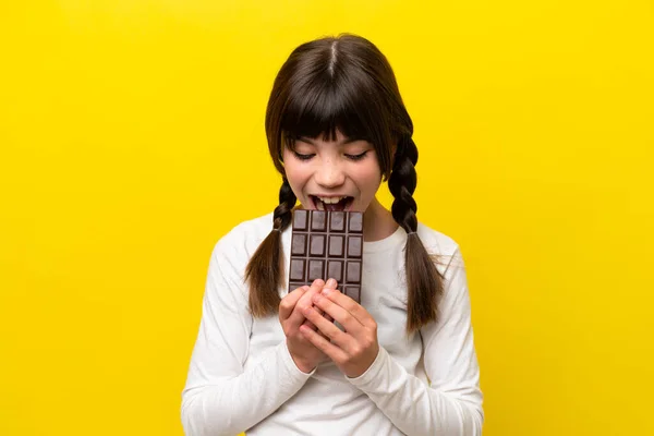 Malá Kavkazská Dívka Izolované Žlutém Pozadí Jíst Čokoládové Tablety — Stock fotografie