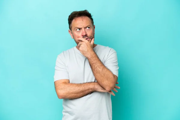 Stock image Middle age caucasian man isolated on blue background having doubts and with confuse face expression