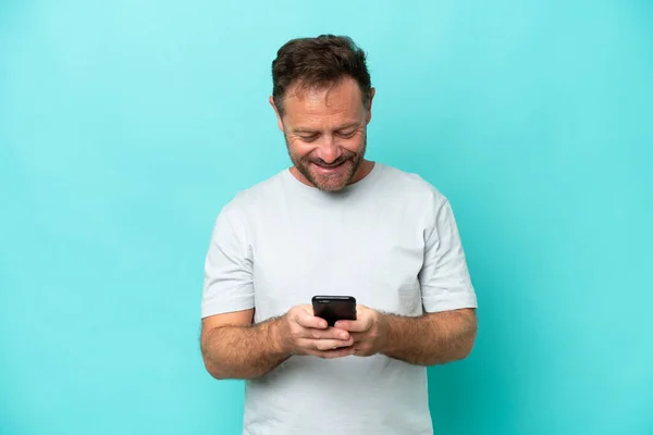 青い背景に隔離された中世の白人男性携帯電話でメッセージを送る — ストック写真