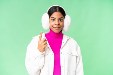 Young African American woman wearing winter muffs over isolated chroma key background pointing with the index finger a great idea