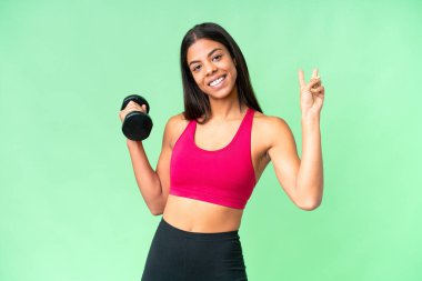 Genç Afrikalı Amerikalı kadın spor kadın halter yapıyor izole edilmiş krom anahtar arka planda gülümsüyor ve zafer işareti gösteriyor