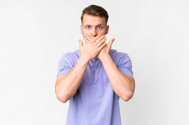 İzole edilmiş beyaz arka planı olan yakışıklı beyaz bir adam elleriyle ağzını kapatıyor.