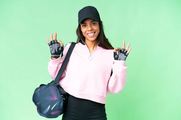 年轻的非裔美国女子体育袋与孤立的彩色关键背景显示一个确定的标志与手指 — 图库照片