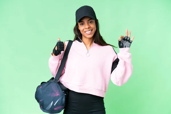 年轻的非洲裔美国女子体育袋与孤立的彩色关键背景显示好迹象和大拇指向上的姿态 — 图库照片