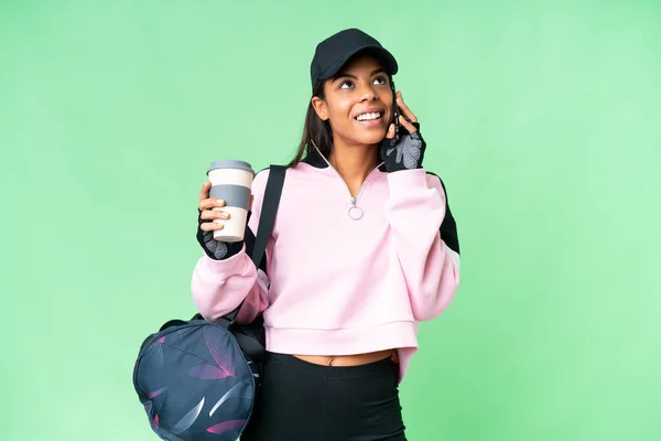 若いですスポーツアフリカ系アメリカ人女性とともにスポーツバッグ上の隔離されたクロマキー背景保持コーヒーを取るためにと携帯電話 — ストック写真