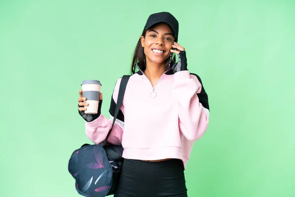年轻的非洲裔美国女子 背着运动包 背负着孤立的彩色关键背景 手里拿着咖啡和手机 — 图库照片