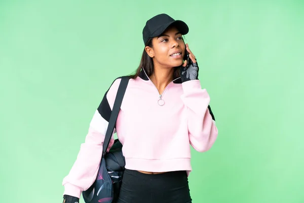 年轻的非洲裔美国女子 背着运动包 背负着孤立的彩色关键背景 与手机保持对话 — 图库照片