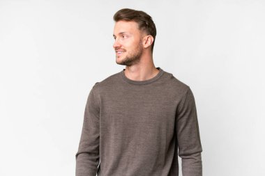 Young handsome caucasian man over isolated white background looking to the side and smiling