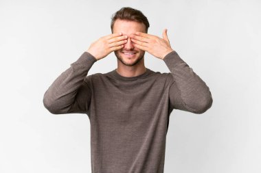 İzole edilmiş beyaz arka planda genç, yakışıklı, beyaz bir adam. Gözleri kapalı ve gülümsüyor.