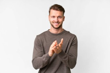 Young handsome caucasian man over isolated white background applauding after presentation in a conference
