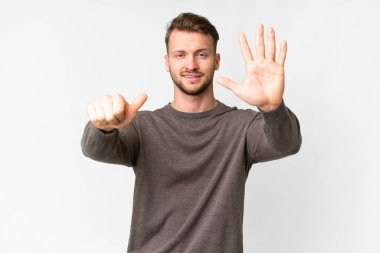 İzole edilmiş beyaz arka planda genç beyaz adam parmakları olan altı kişi sayıyor.