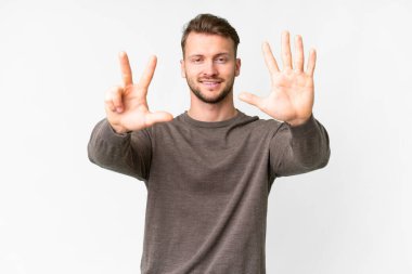 İzole edilmiş beyaz arka planda genç beyaz adam sekiz parmaklı sayıyor.