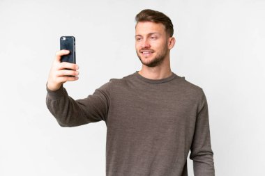 İzole edilmiş beyaz arka planı olan yakışıklı beyaz bir adam selfie çekiyor.