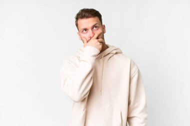Young handsome caucasian man over isolated white background having doubts and with confuse face expression