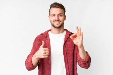 Young handsome caucasian man over isolated white background showing ok sign and thumb up gesture