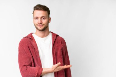 Young handsome caucasian man over isolated white background presenting an idea while looking smiling towards