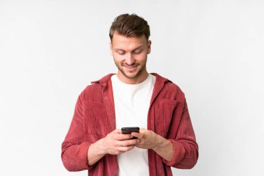 Young handsome caucasian man over isolated white background sending a message with the mobile