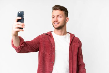 Young handsome caucasian man over isolated white background making a selfie