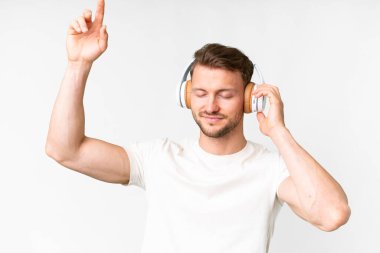 Beyaz arka planda yaşayan yakışıklı beyaz adam müzik ve dans dinliyor.