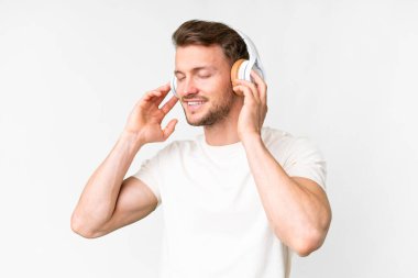 Young handsome caucasian man over isolated white background listening music and singing