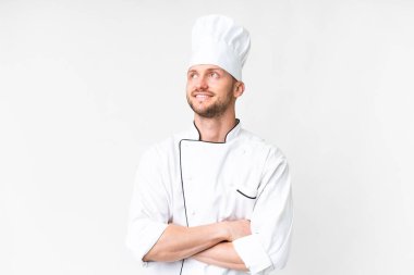 Young caucasian chef over isolated white background looking up while smiling