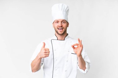 Young caucasian chef over isolated white background showing ok sign and thumb up gesture