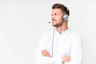 Tele pazarlamacı Kafkasyalı bir adam izole edilmiş beyaz arka planda mutlu ve gülümseyen bir kulaklıkla çalışıyor.