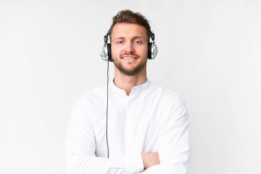 Tele pazarlamacı, beyaz arka planda kulaklıkla çalışan beyaz bir adam kollarını ön cephede çapraz tutuyor.