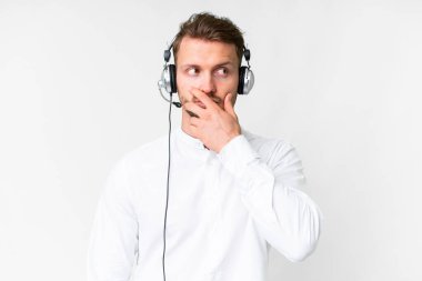 Tele pazarlamacı, beyaz arka plan üzerinde kulaklıkla çalışan beyaz bir adam. Şüpheleri var ve kafası karışmış bir yüz ifadesi var.