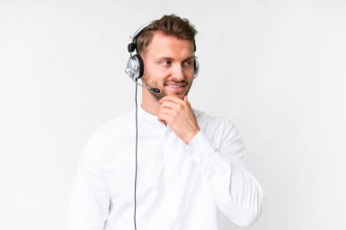 Tele pazarlamacı, beyaz arka plan üzerinde çalışan beyaz kulaklıklı beyaz bir adam yan tarafa bakıyor.