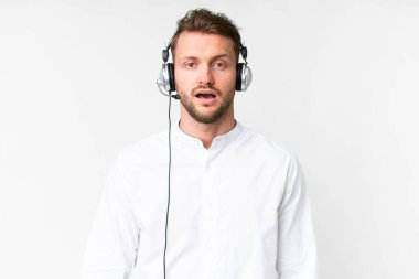 Tele pazarlamacı beyaz kulaklıkla çalışan beyaz bir adam. Şaşırtıcı bir yüz ifadesi var.